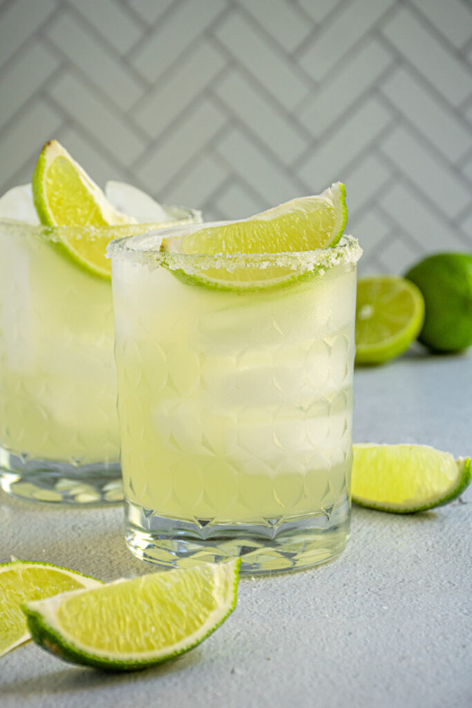 A glass with a salted rim and a lime wedge filled with mocktail margarita.