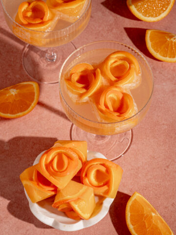 A small bowl and coupe glass with orange rose ice cubes.