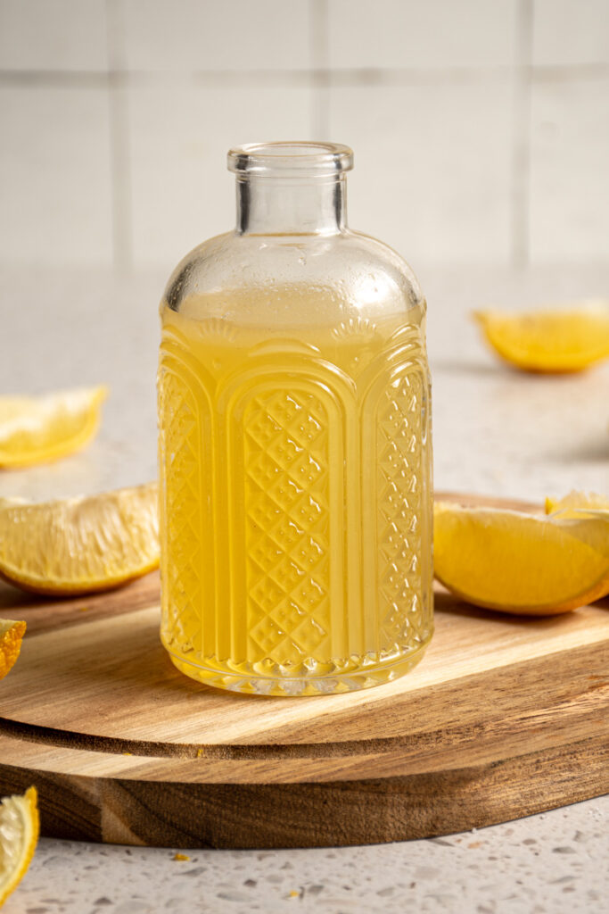 A jar with yellow colored lemon ginger shrub.