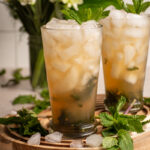 A pair of large glasses with crushed ice and filled mint julep mocktails.