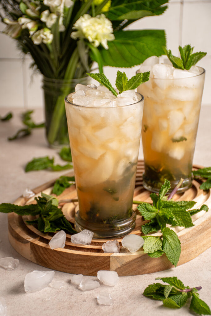 A pair of large glasses with crushed ice and filled mint julep mocktails.