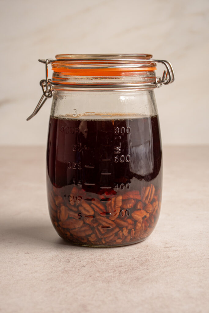 Pecans in bourbon in a glass jar.