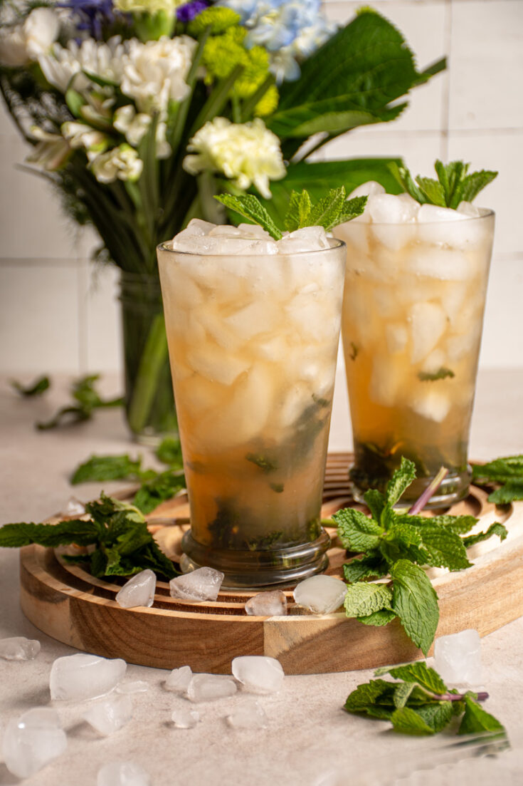 A pair of large glasses with crushed ice and filled mint julep mocktails.