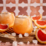 Stemless wine glass filled with grapefruit elderflower spritz surrounded by grapefruit slices.